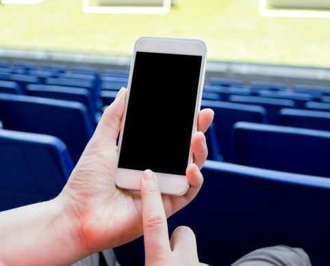 Smartphone into a person's hand who sits on stands