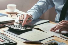 Businessman works on desk office using a calculator to calculate the accounting numbers