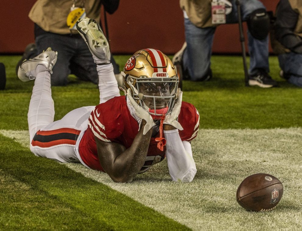 American football player celebrates a touchdown by smiling and stretching on the field