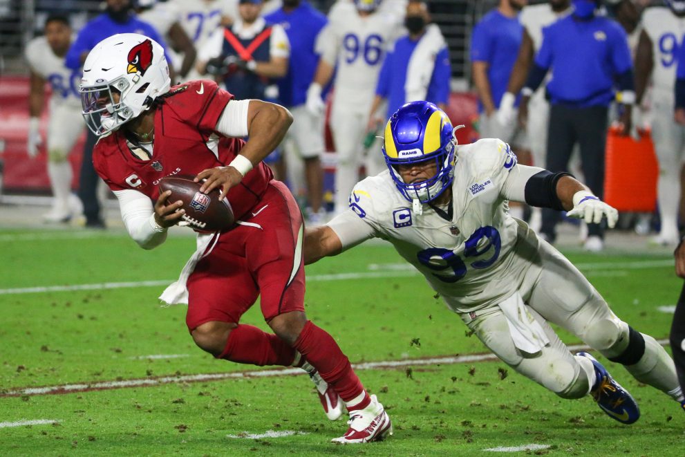 American football player runs the ball under pressure from a player of the opposite team