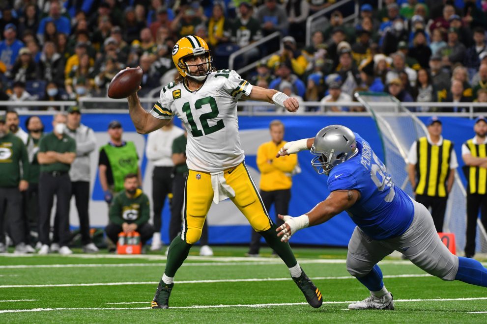 American football player throws the ball under pressure from a player of the opposite team