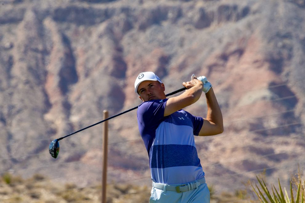 Golf player tees off from a hole during a game