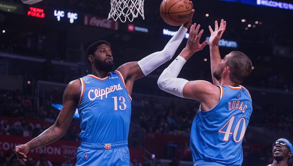 Basketball players jump towards a basket