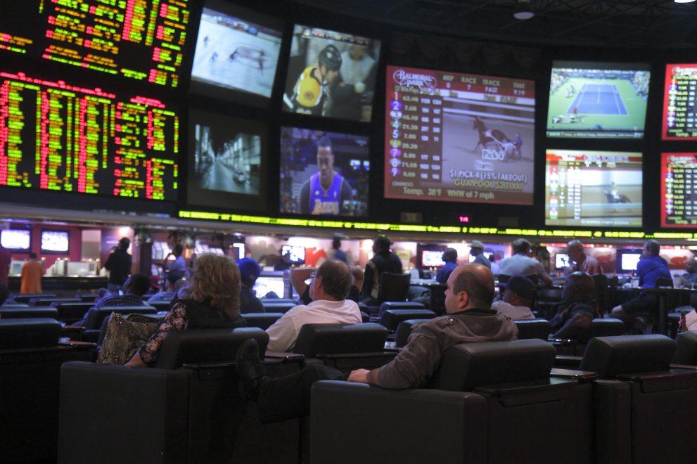 Men and women watch on many monitors races, sports book, betting, odds, tennis, gambling