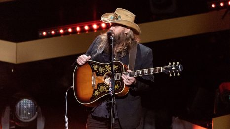 A country singer who has an electric guitar performs on a stage