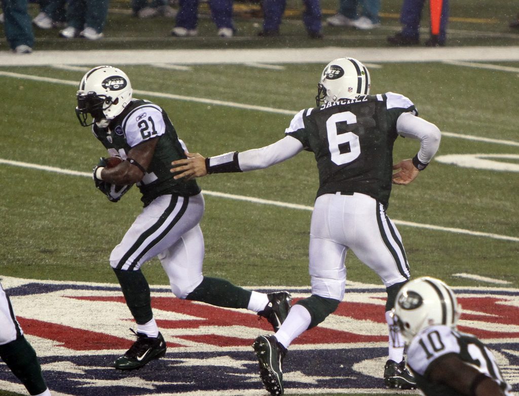 American football players pass the ball during the match