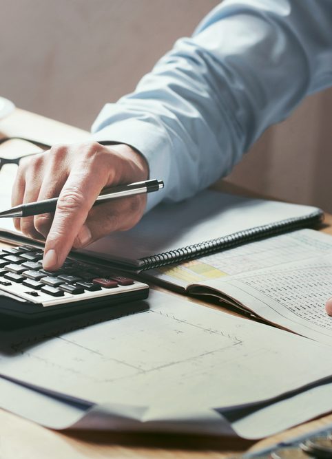 Businessman working on desk office with using a calculator to calculate the numbers finance accounting concept