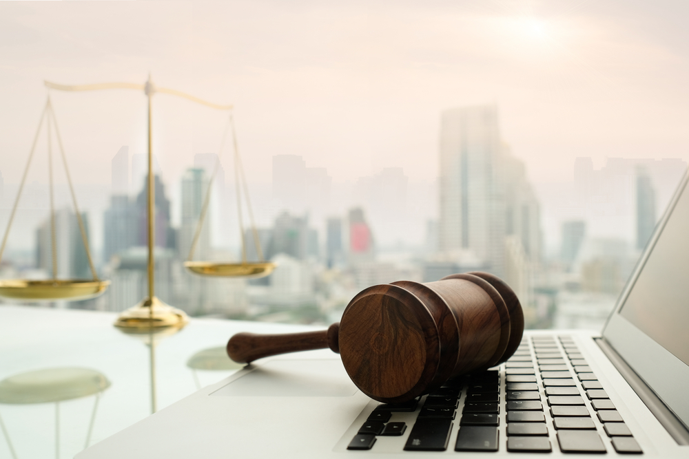 Judge gavel on computer with scales of justice on desk of lawyer.