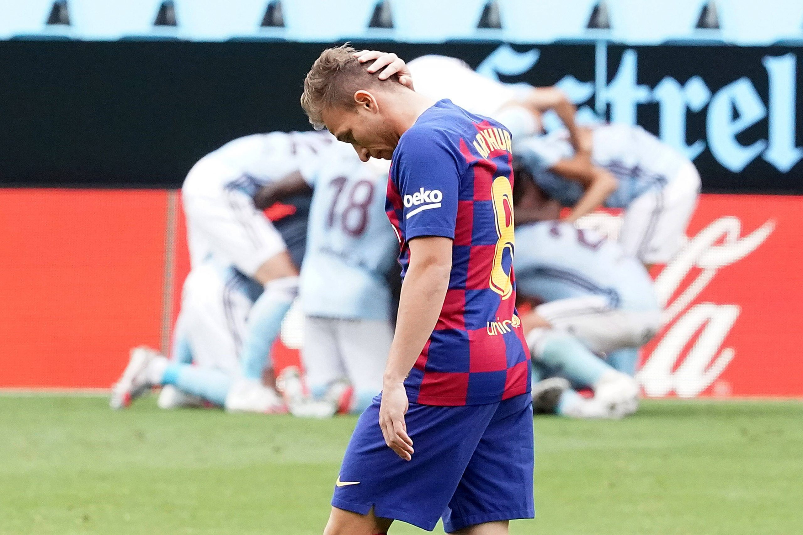 Football player looks dejected during the opposite team players celebrate after scoring