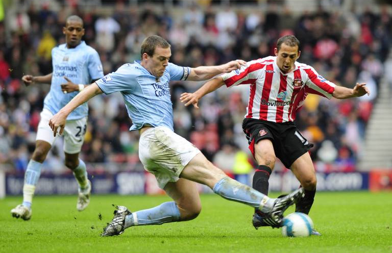 Three football players run to the ball during a match