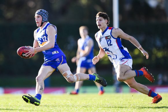 Australian rules football player runs with the ball during a match
