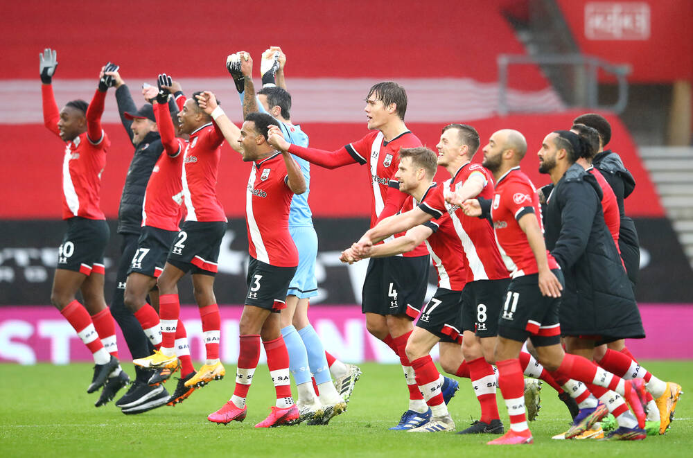 Football players celebrate victory in front of the fans after the match ends