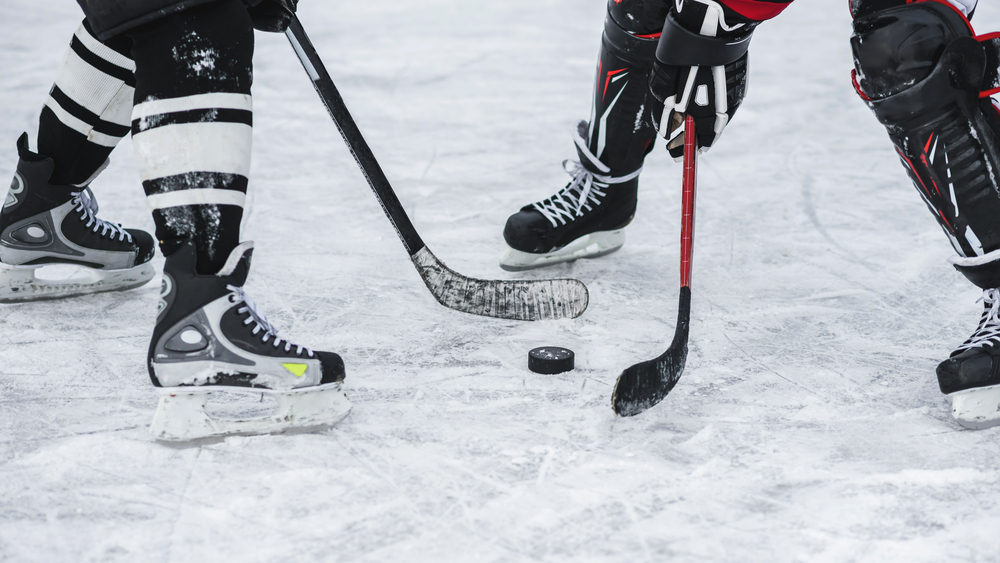 Close-up of puck between two hockey sticks during a hockey game