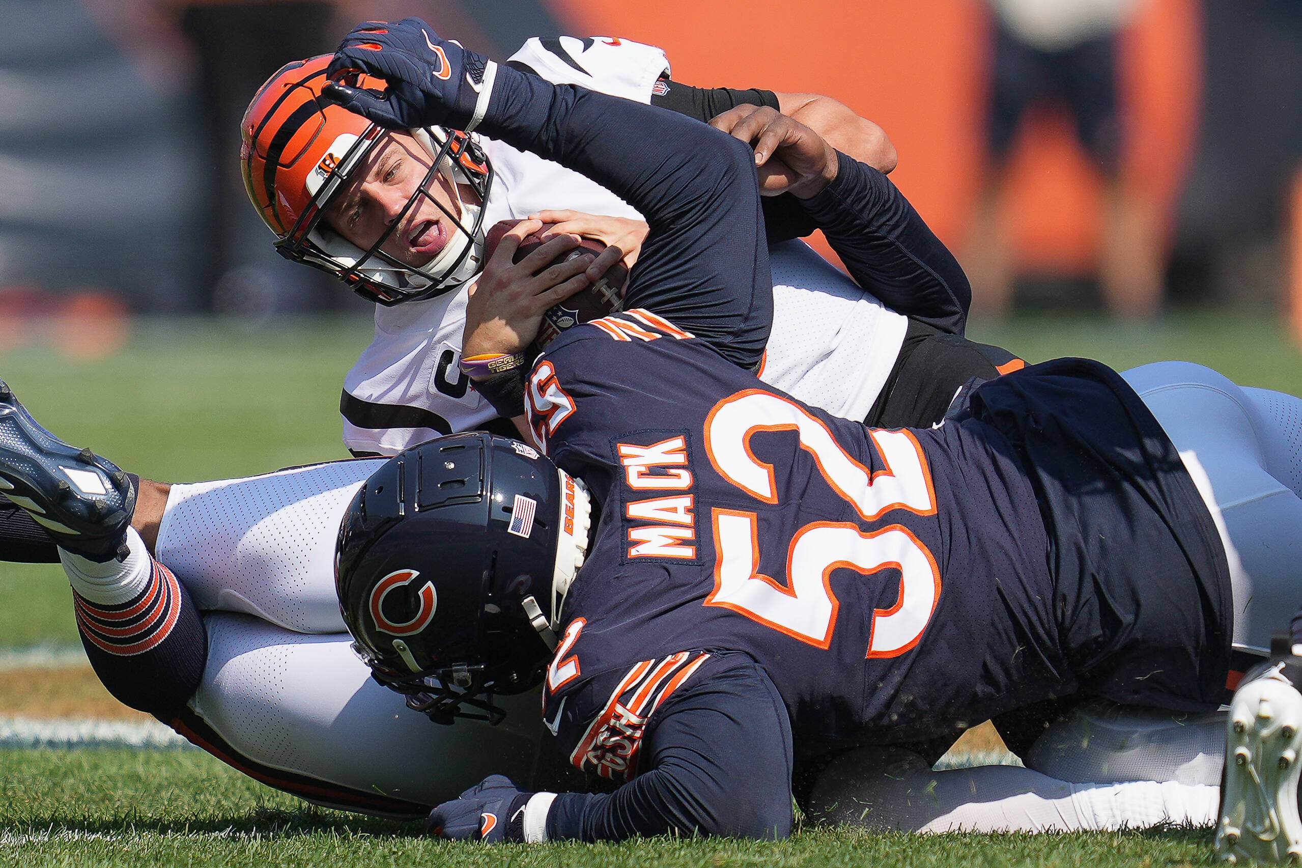 American football player is tackled by two opponent team players during a game