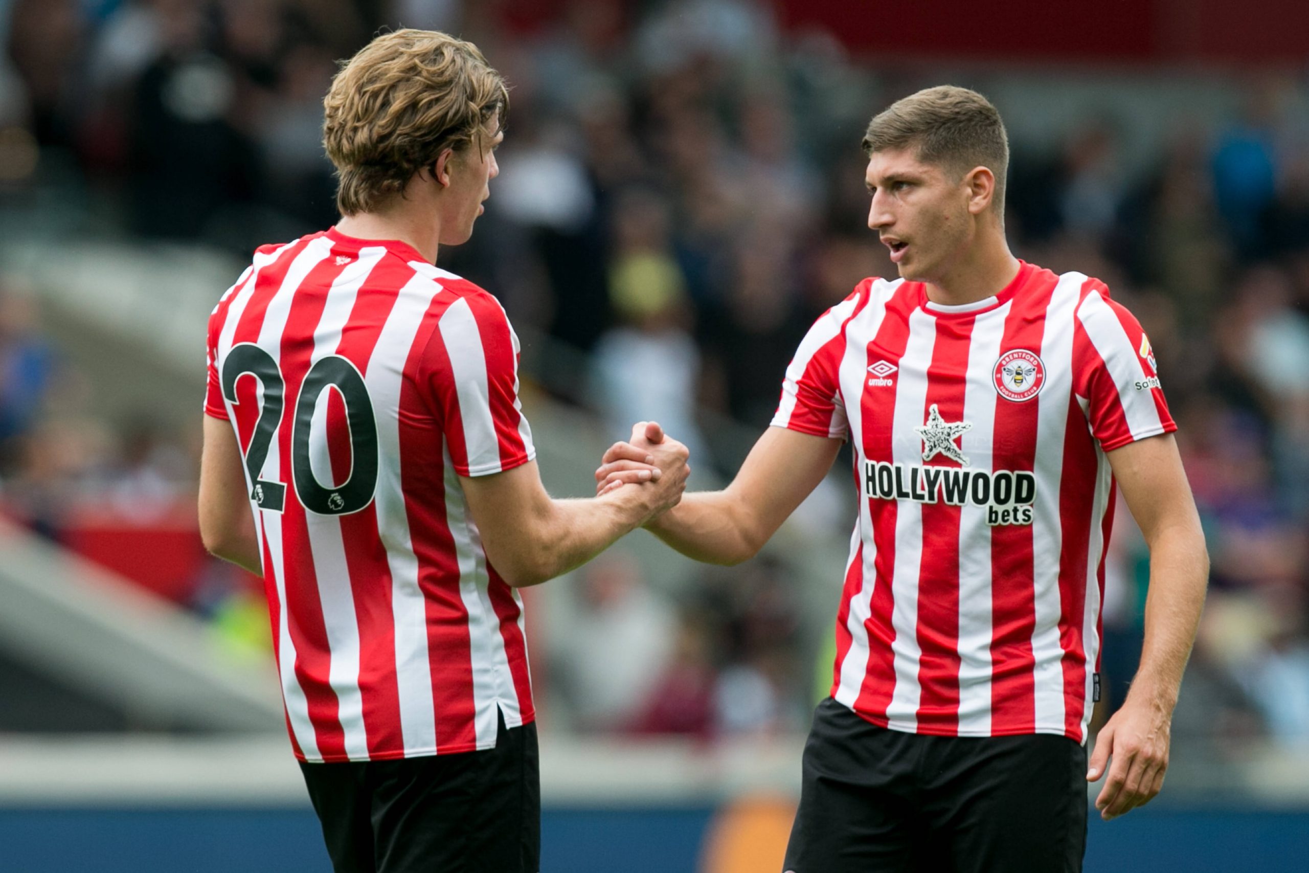 Two football players talk and shake hands during a game