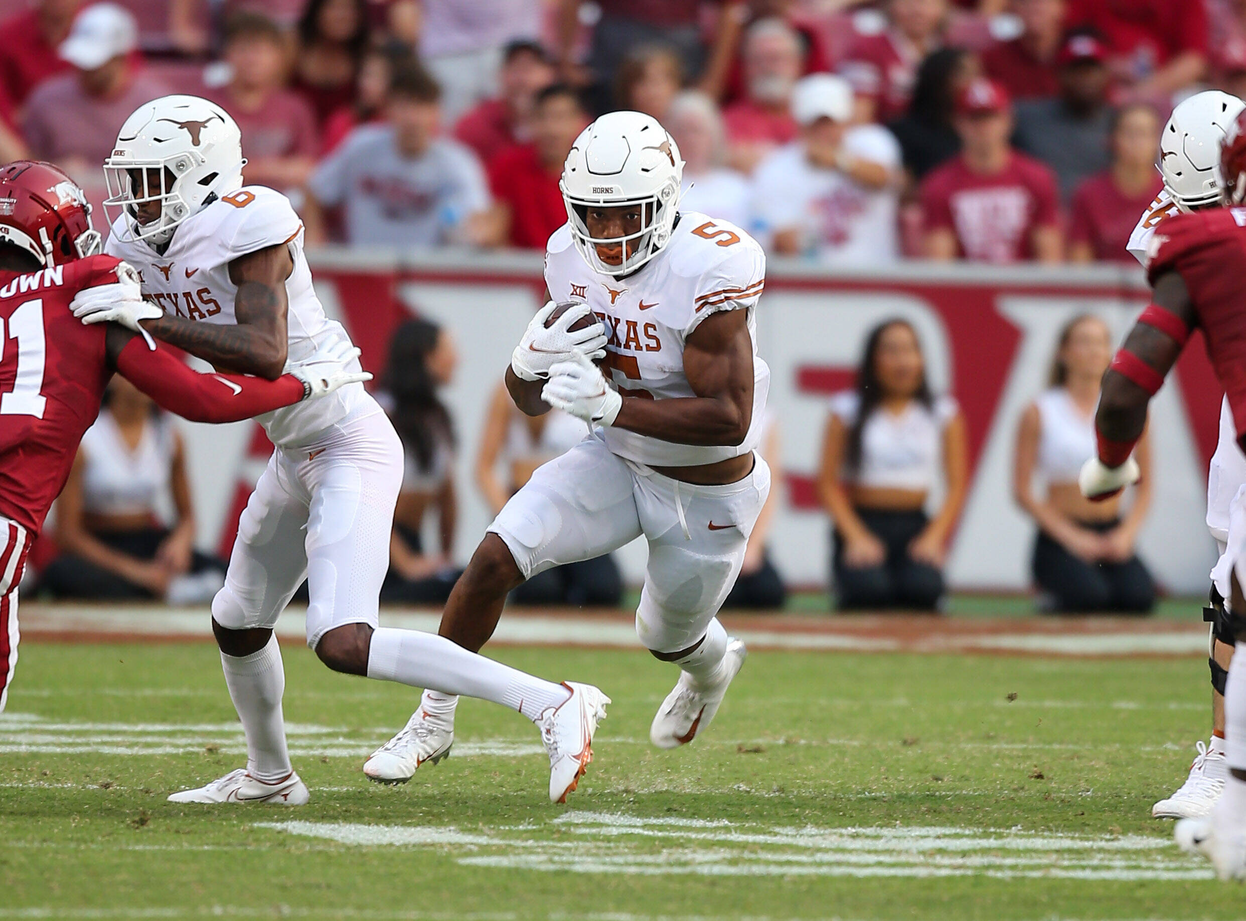 An american football player running back his team mate who brings the ball up the field