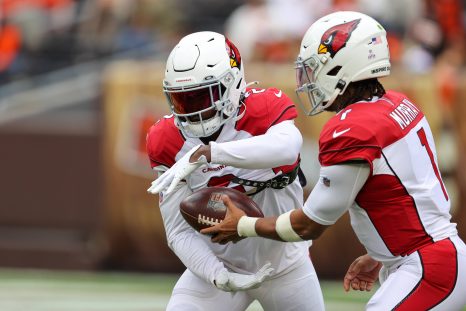 Two american football players pass the ball during a game