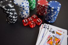 Blue, black, green, white and black casino chips, five dices and playing cards on a table