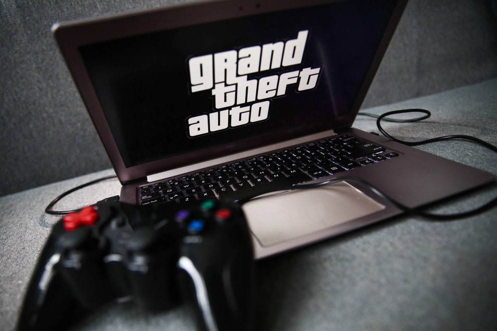 Grand Theft Auto logo displayed on a laptop screen and a gamepad