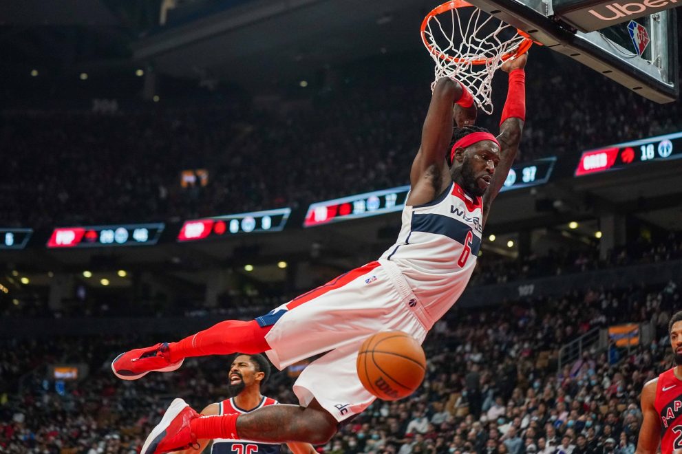 Basketball player hangs on the rim after a dunk