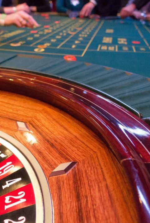 A piece of roulette wheel and players hands placing their bets on the bet table