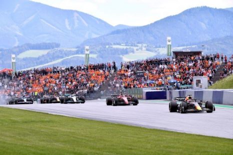 Cars on the track at the Austrian Grand Prix, crowd and mountains in the background