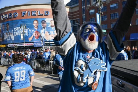 Detroit fan cheers as he walks along the sidewalk outside of Ford Field